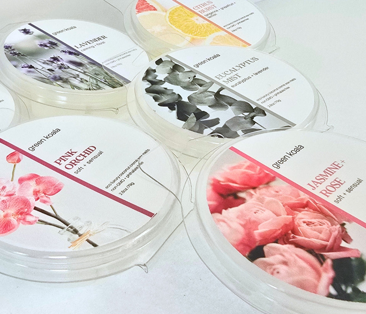 A variety of nontoxic wax melts made by Green Koala laid out on top of a white background. Scents pictured include:  Pink Orchid, Lavender, Eucalyptus List, Citrus