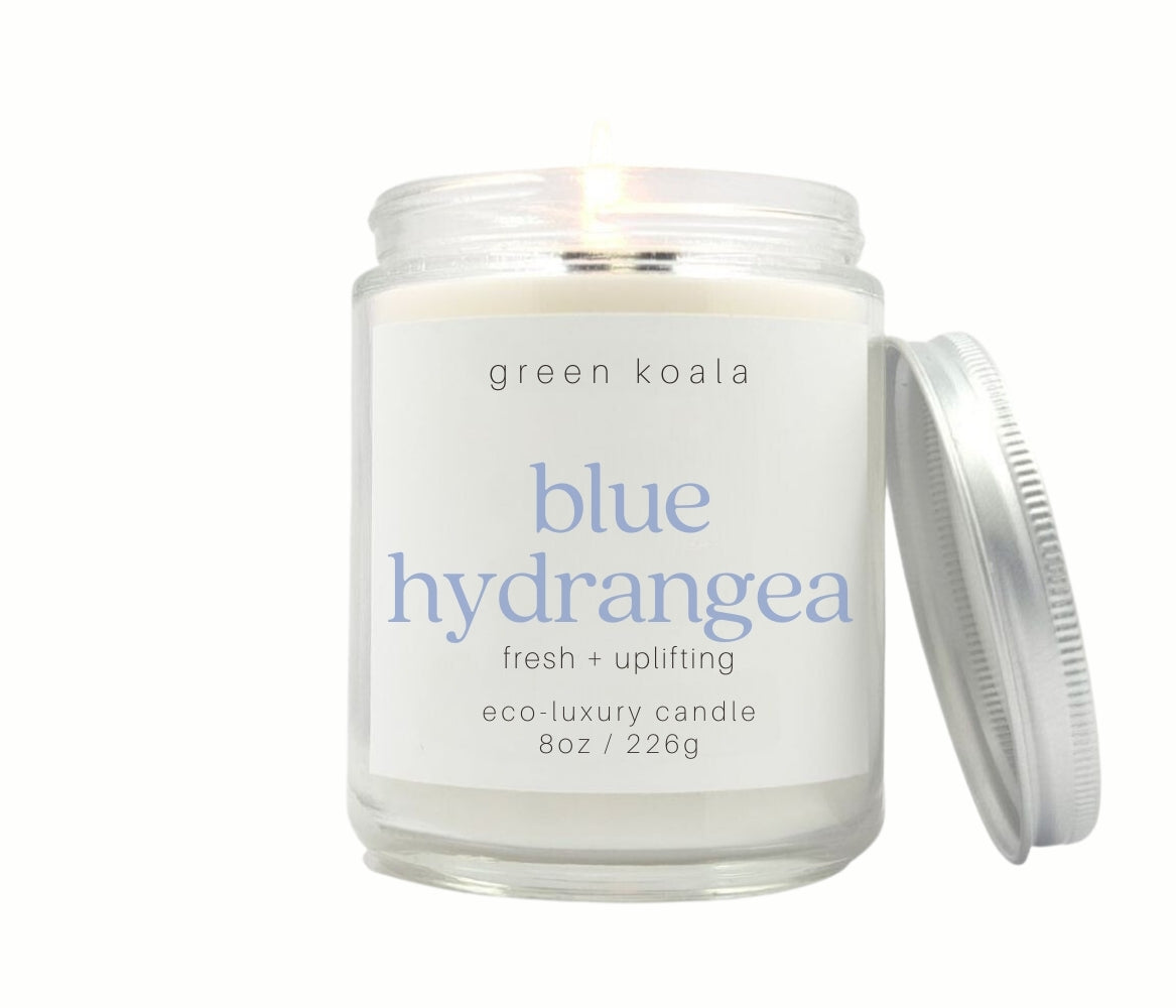 8oz Blue Hydrangea scented non-toxic candle in aglass jar with a silver lid.