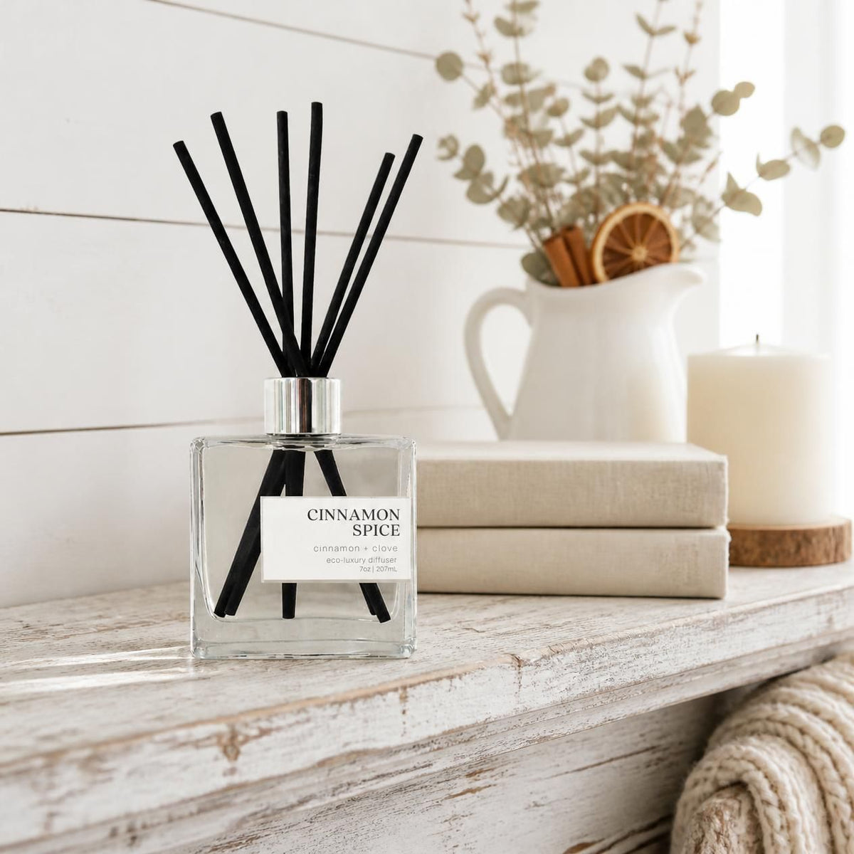 Green Koala Cinnamon Spice non-toxic reed diffuser on a white farmhouse mantel with linen books and a knit throw