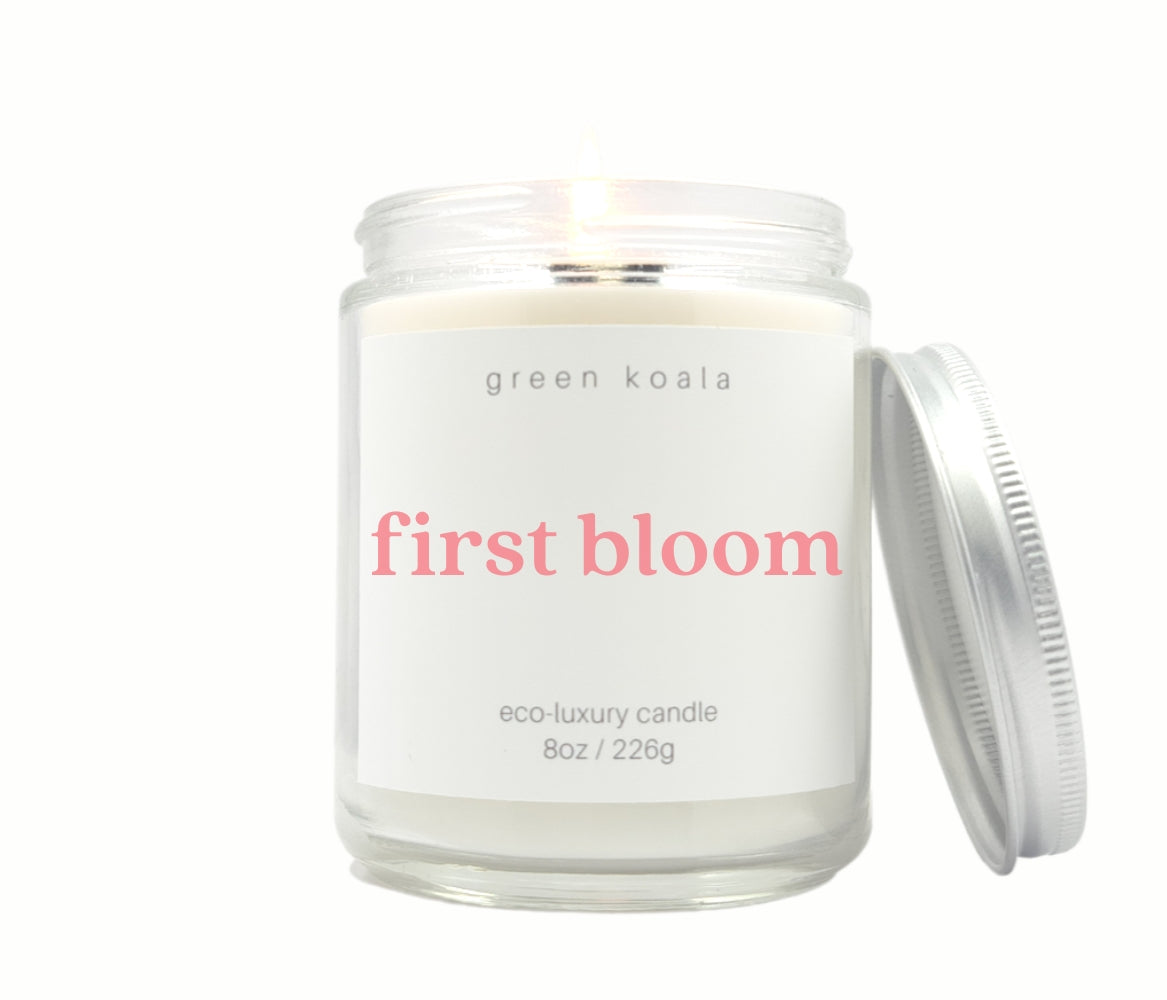 First Bloom Green Koala 8oz candle with floral scent, featuring a soft, elegant design and delicate floral accents.