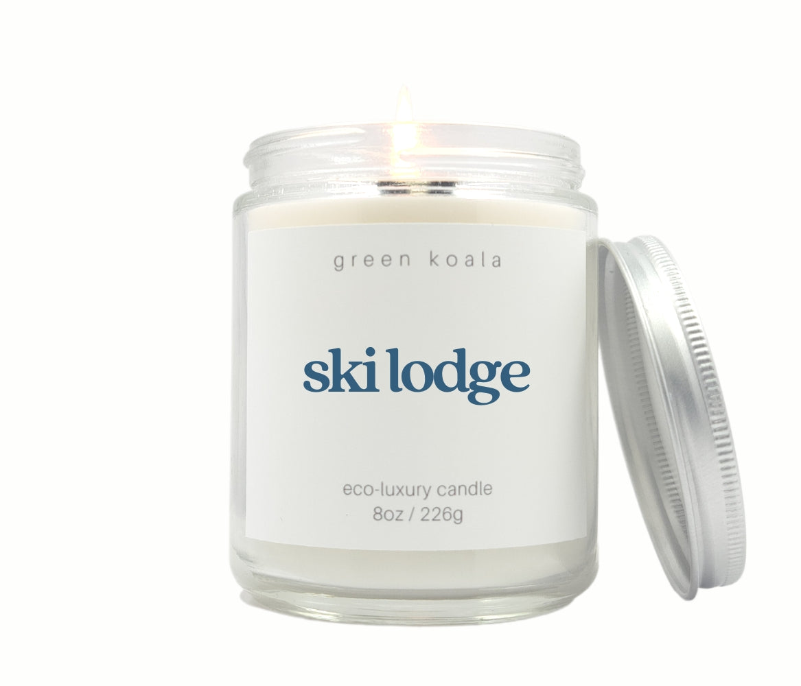 Green Koala Ski Lodge 8 oz. candle burning with lid to the side