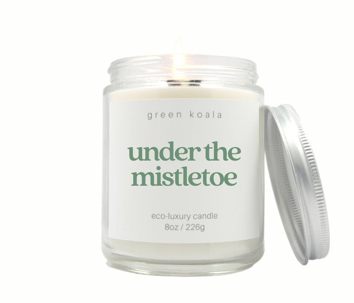 Green Koala Under the Mistletoe 8 oz. candle burning with lid to the side