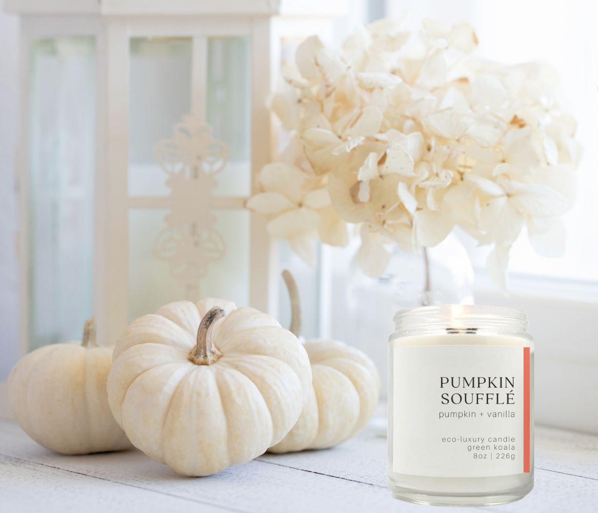 Pumpkin souffle candle burning on a table with fall decor. 
