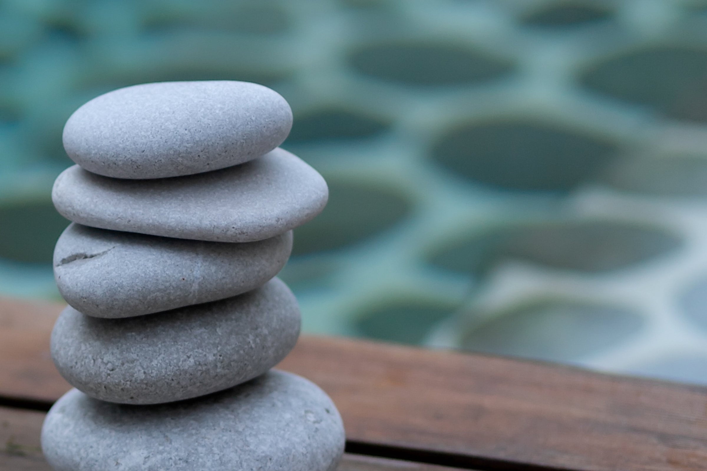 Image of stacked rocks with blue water background. 
