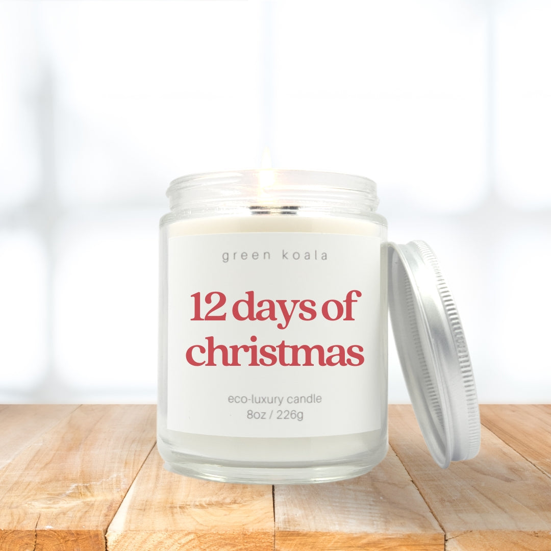 Image of 12 Days of Christmas candle in a glass jar with a silver lid resting on the side on a wooden shelf.  