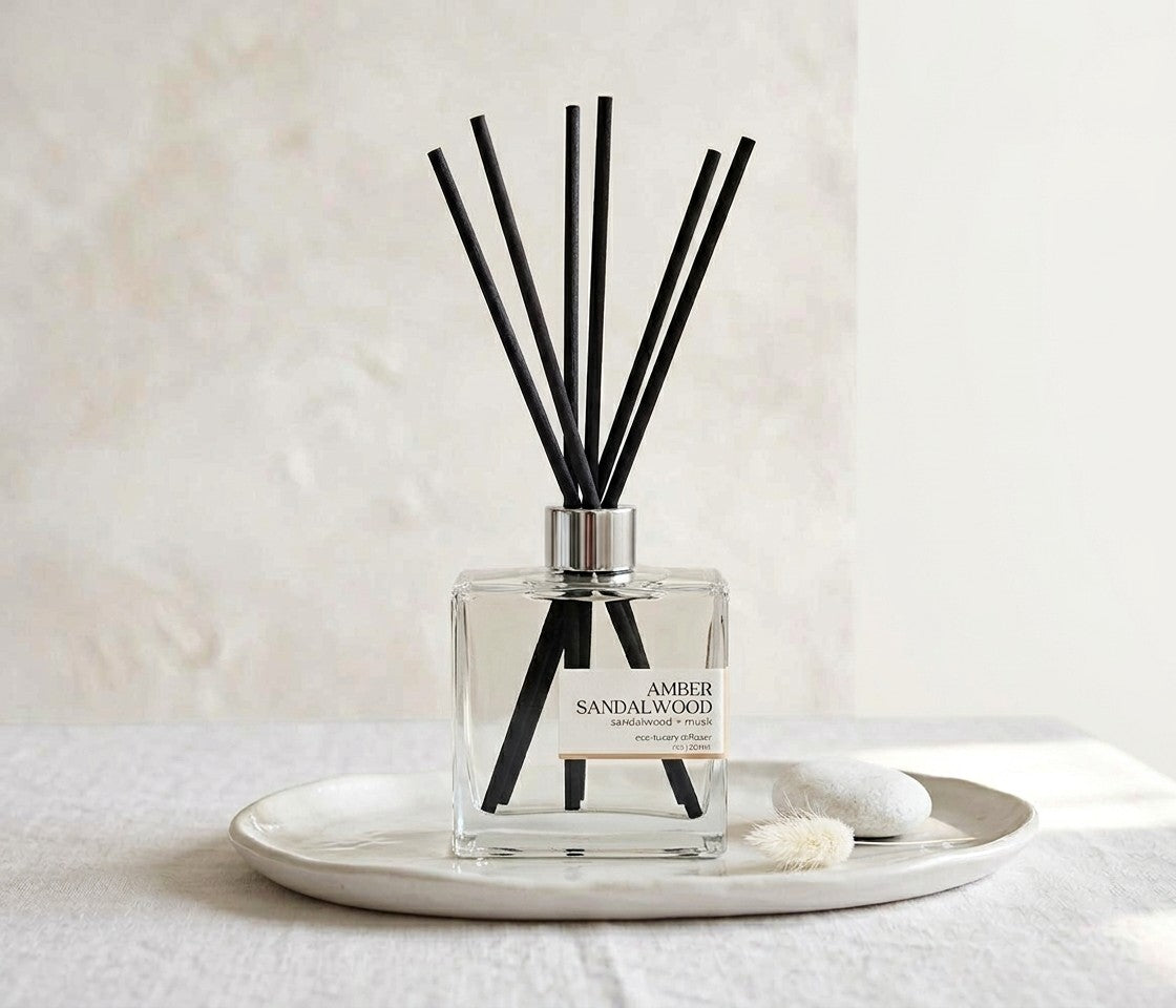 Amber Sandalwood Reed diffuser with black sticks in a clear bottle on a white surface