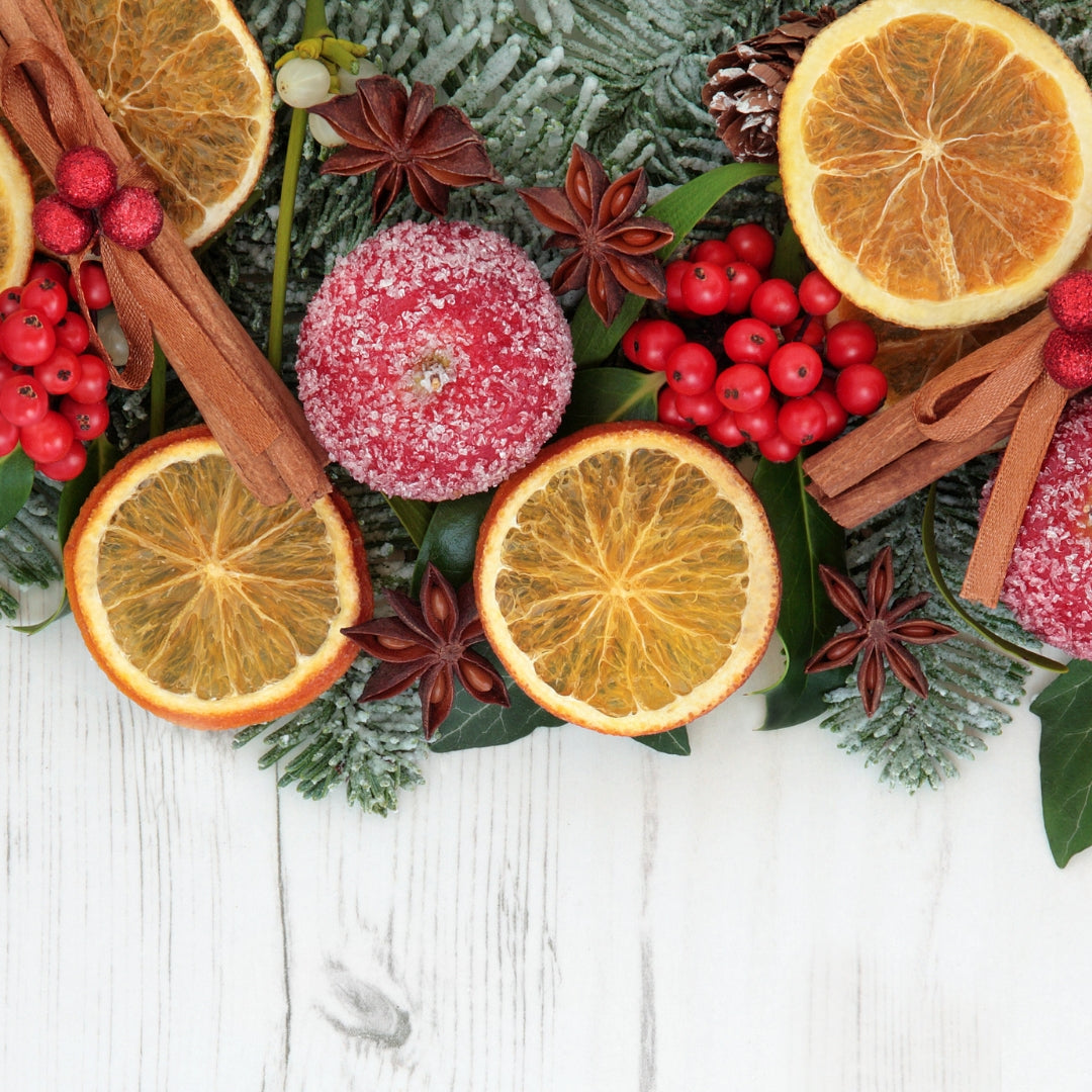 Array of orange slices, cinnamon sticks, pine, and holly berries.