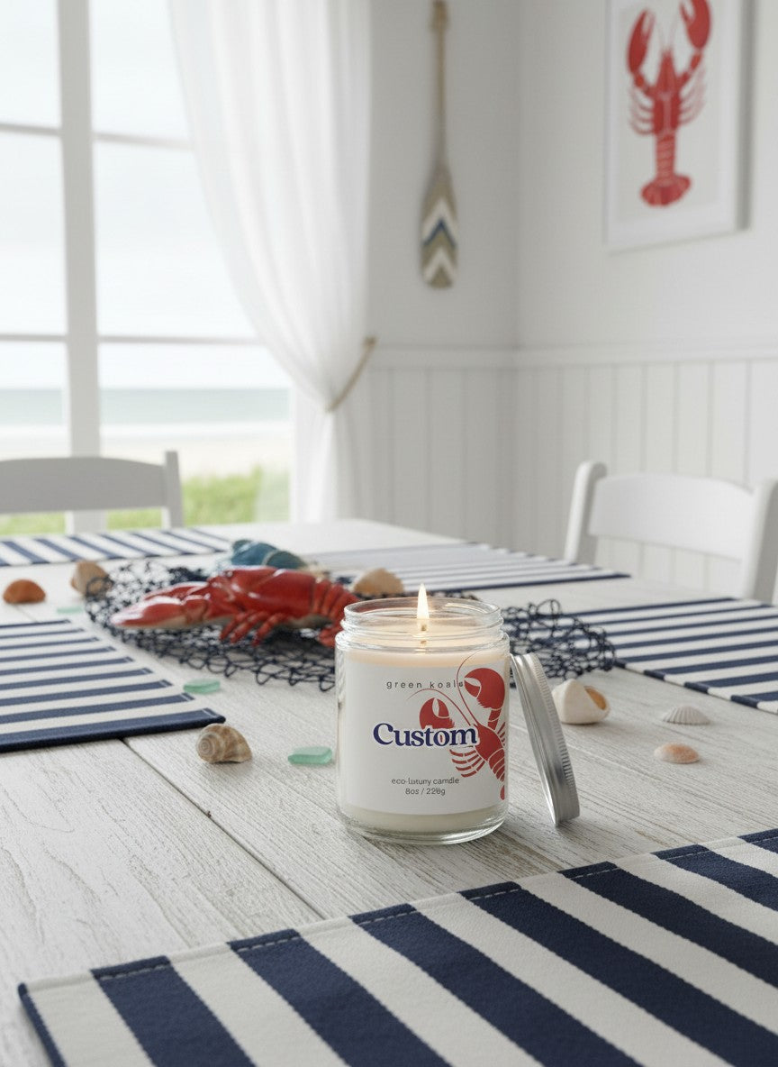 Candle with lobster design on a table setting with striped tablecloth and ocean view.