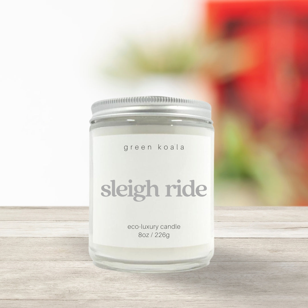 Image of Sleighride candle in a glass jar with silver lid on a wooden shelf. 