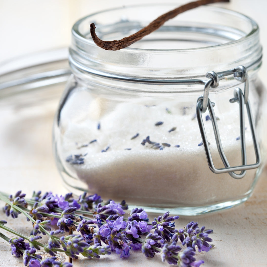 Jar of white sugar, lavender blooms, and vanilla beans. 