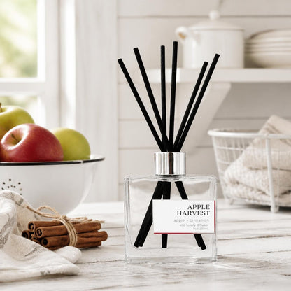 Green Koala Apple Harvest non-toxic reed diffuser on a white rustic farmhouse kitchen counter with fresh apples and cinnamon sticks
