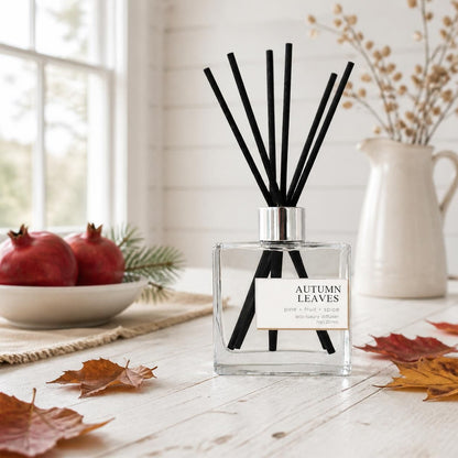 Green Koala Autumn Leaves non-toxic reed diffuser on a white rustic farmhouse table with autumn leaves and pomegranates