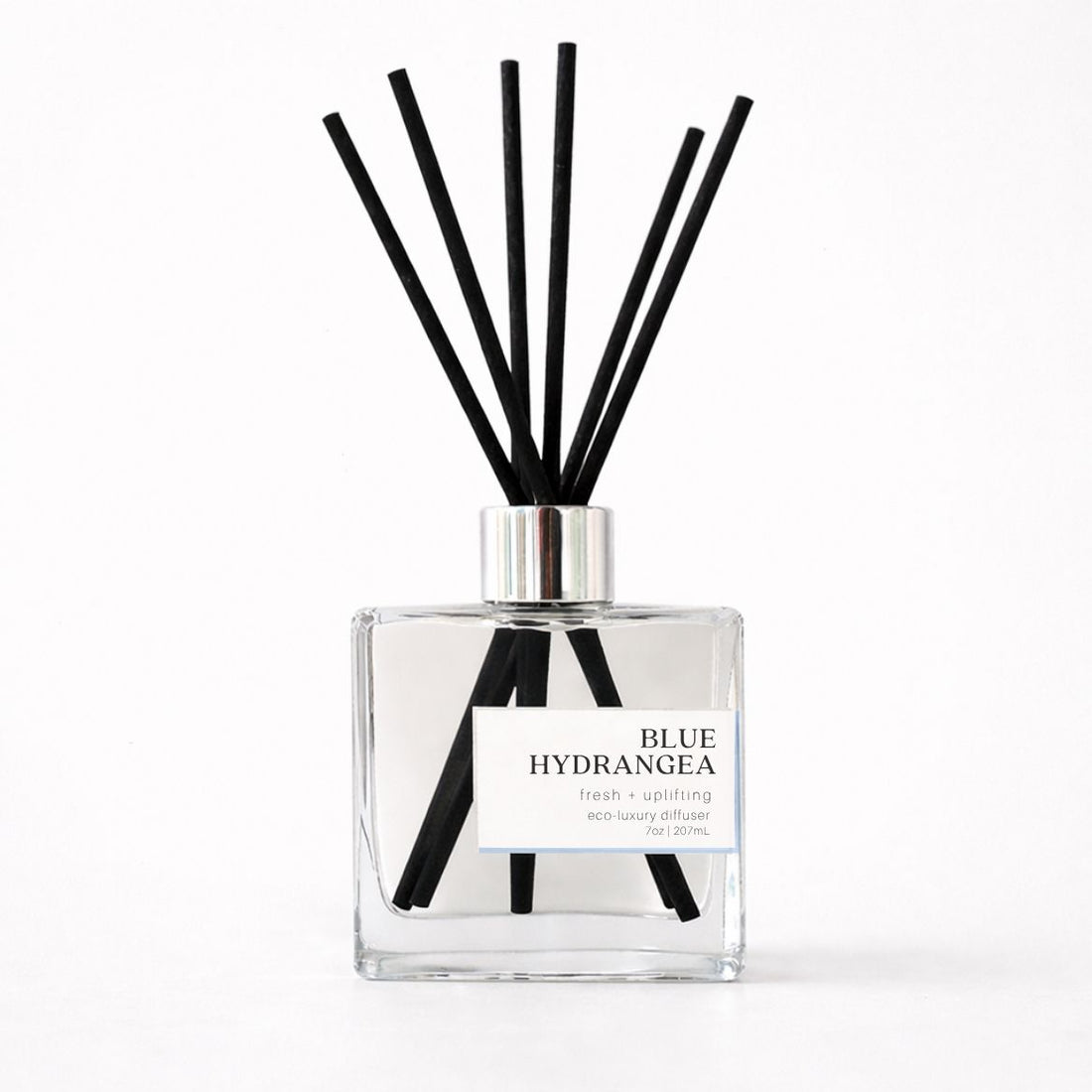 Clear diffuser bottle with black reeds labeled &