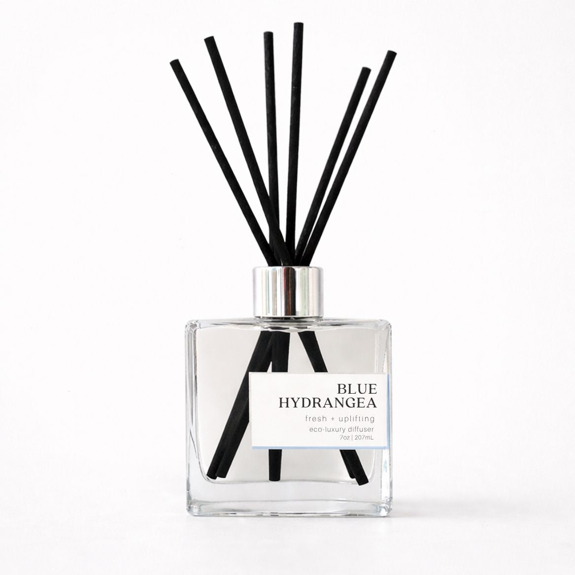 Clear diffuser bottle with black reeds labeled &