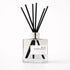 Clear diffuser bottle with black reeds labeled &