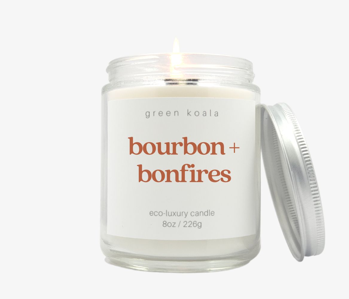 8oz Bourbon + bonfires candle in glass jar with silver lid leaning on side. Made with coconut wax and non-toxic fragrance.