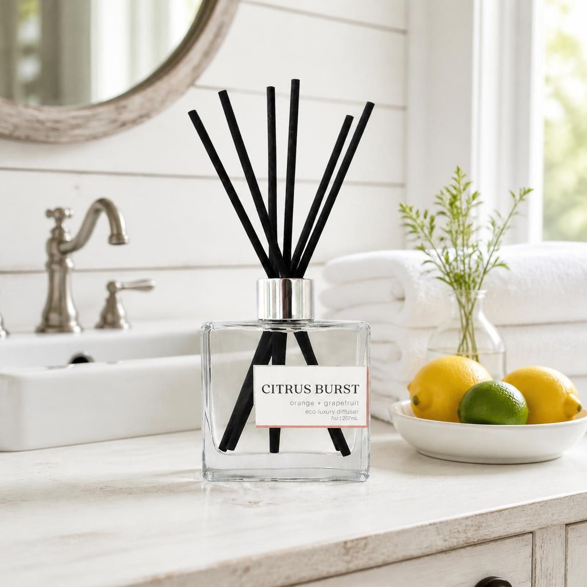 Green Koala Citrus Burst non-toxic reed diffuser on a white farmhouse bathroom vanity with white towels and fresh lemons