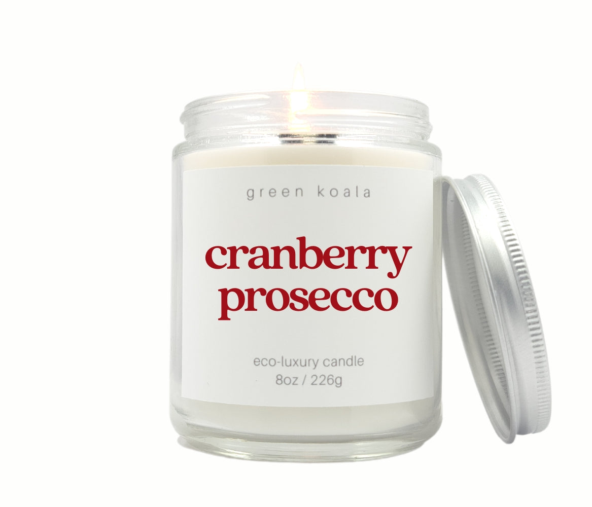 Green Koala Cranberry Prosecco 8 oz. candle burning with lid to the side
