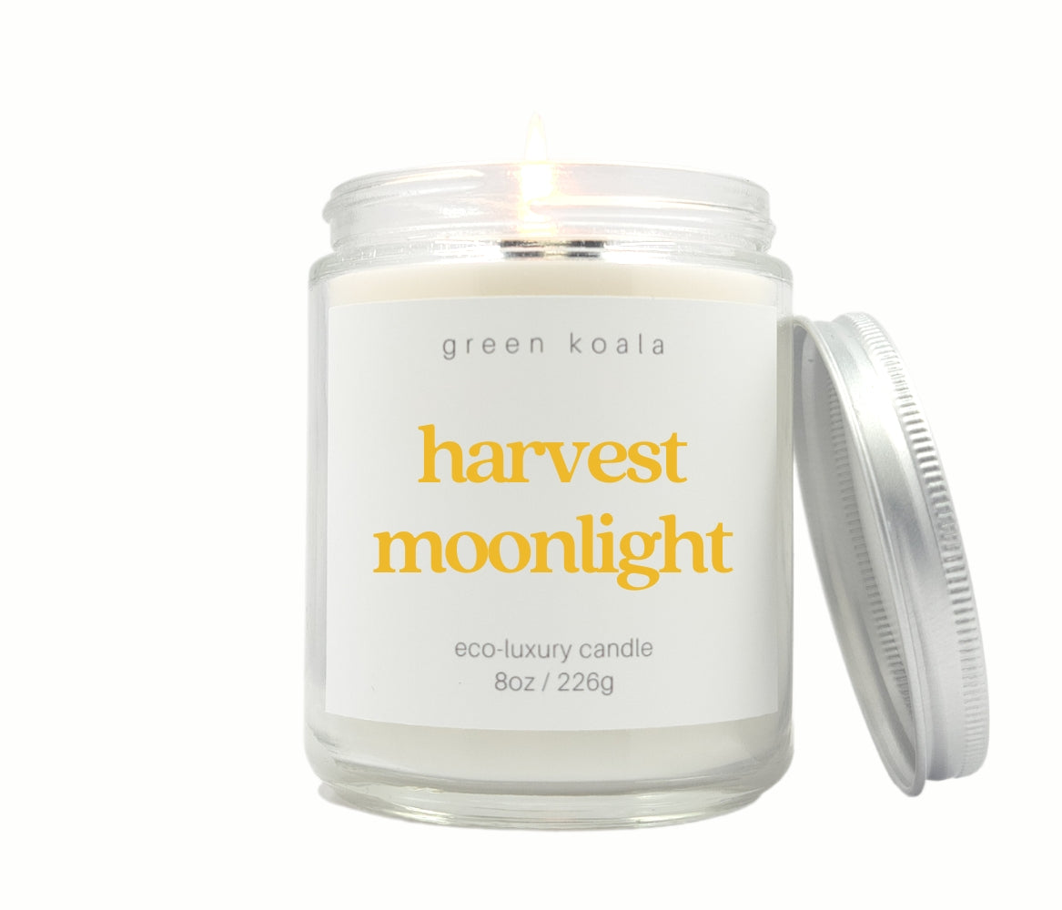 Green Koala Harvest Moonlight 8 oz. candle burning with lid to the side