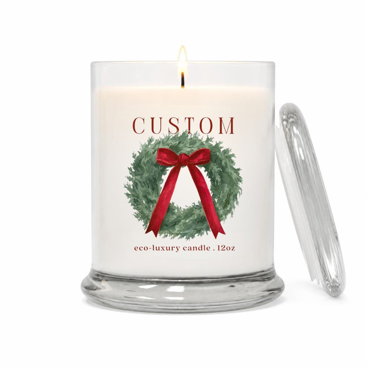 Green Koala personalized holiday wreath 12oz candle with cranberry bow and custom town name label, lit, with glass lid on a white background