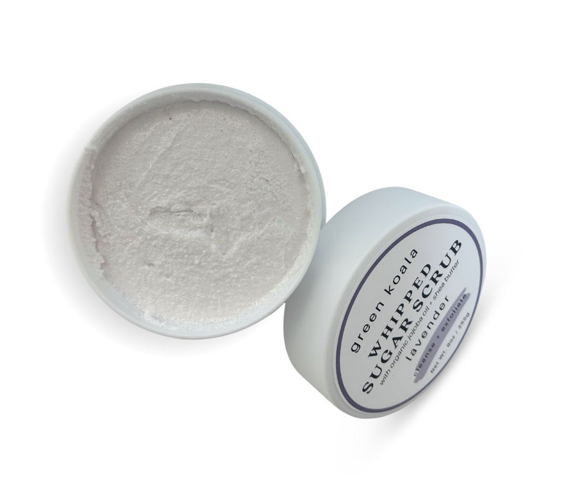 9oz Lavender Sugar Body Scrub jar with lid leaning on side, showcasing whipped texture and calming floral scent, exfoliates and hydrates skin.