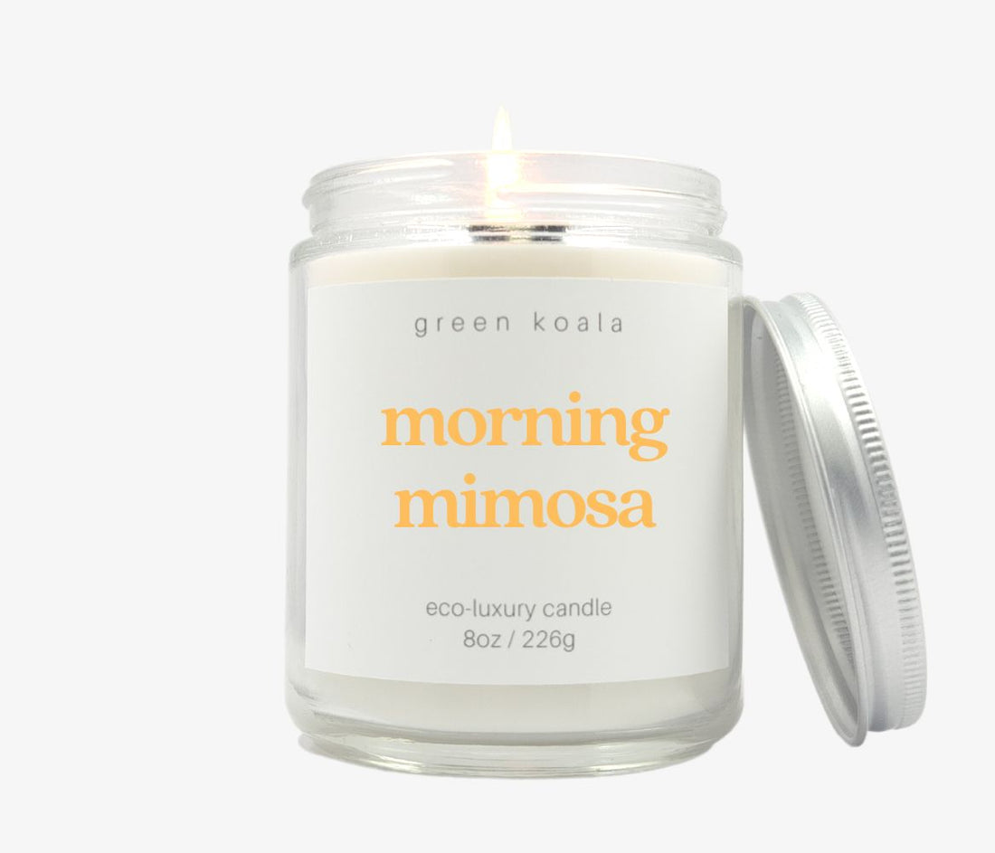 Morning mimosa candle in an 8oz jar burning with silver lid slanted on side