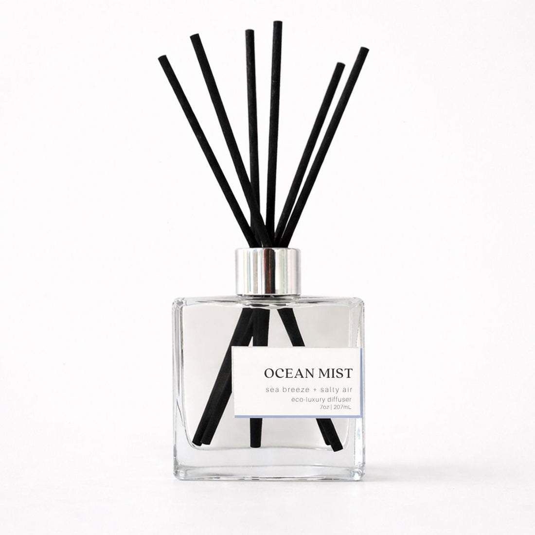 Clear diffuser bottle with black reeds labeled &