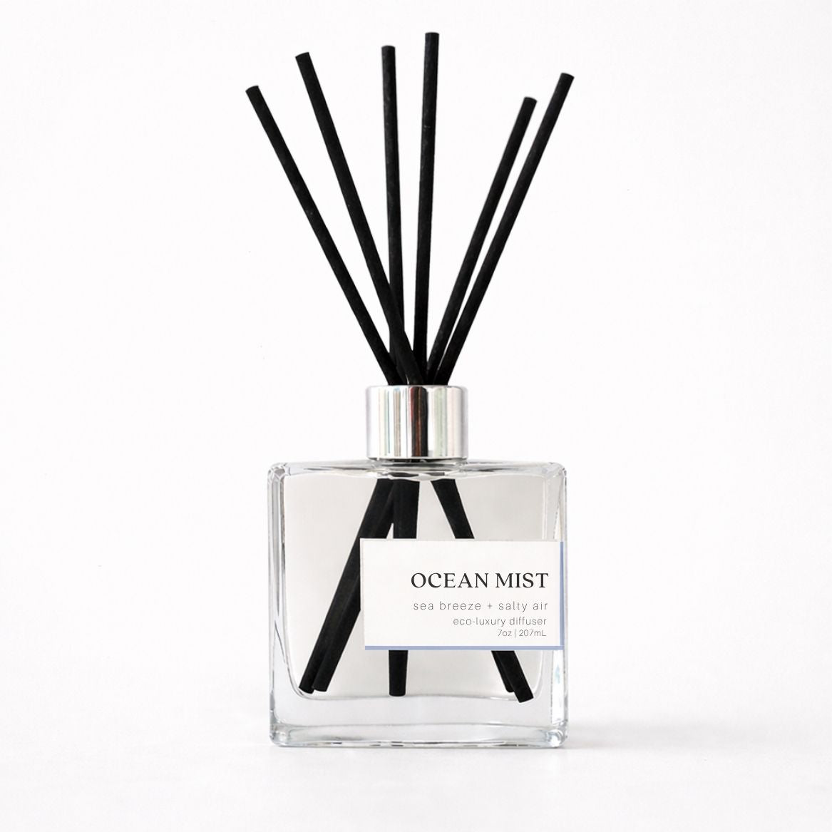 Clear diffuser bottle with black reeds labeled &