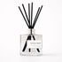 Clear diffuser bottle with black reeds labeled &