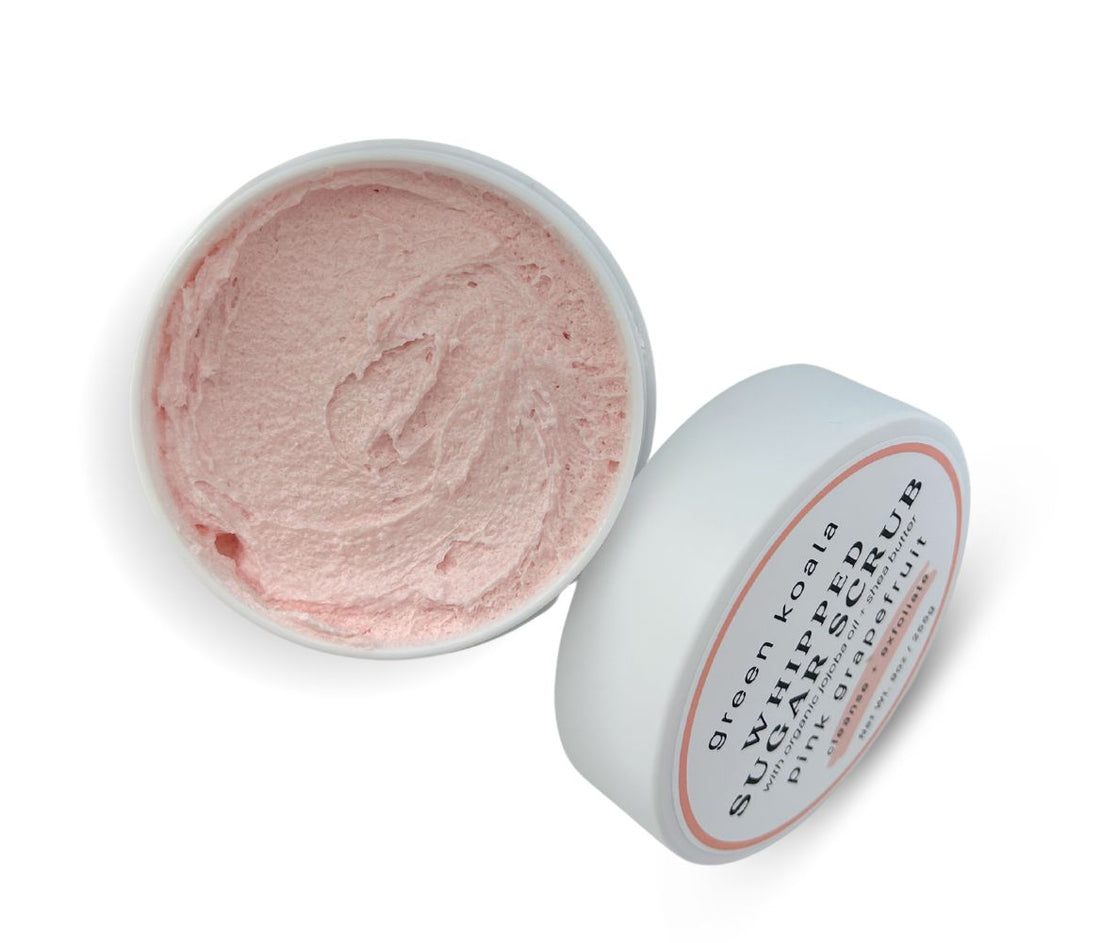 9oz Pink Grapefruit Sugar Body Scrub jar with lid leaning on side, showcasing whipped texture and invigorating citrus scent, cleanses, exfoliates, and hydrates skin.