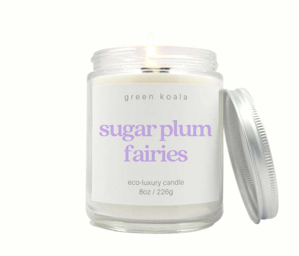 Green Koala Sugar Plum Fairies 8 oz. candle burning with lid to the side