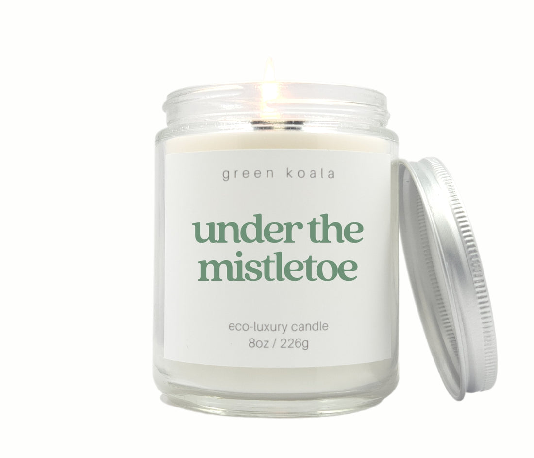 Green Koala Under the Mistletoe 8 oz. candle burning with lid to the side