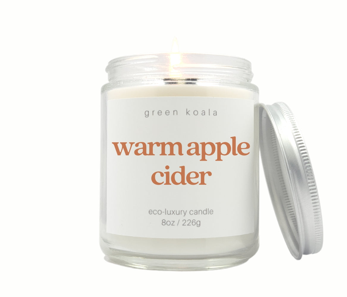 Green Koala Warm Apple Cider 8 oz. candle burning with lid to the side